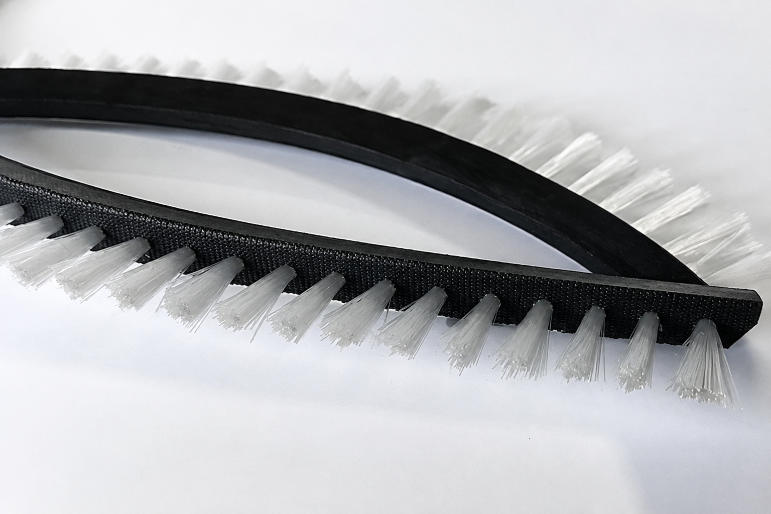 Trapezoid V-belt brush for confined conveyor contact