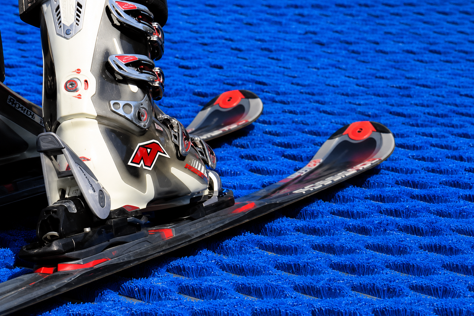 Skis resting on a blue diamond bristle ski mat surface