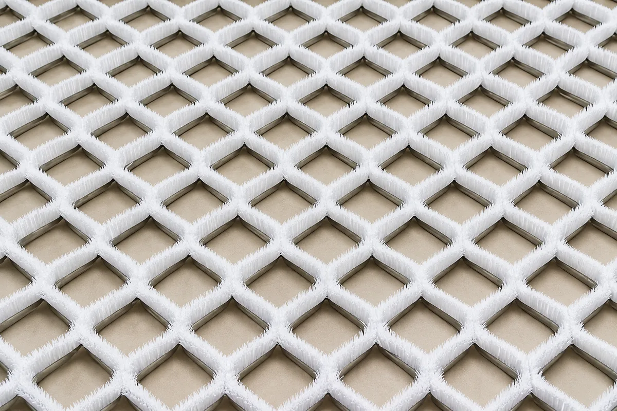 Diamond-pattern dry ski slope mat with white bristles and metal channels