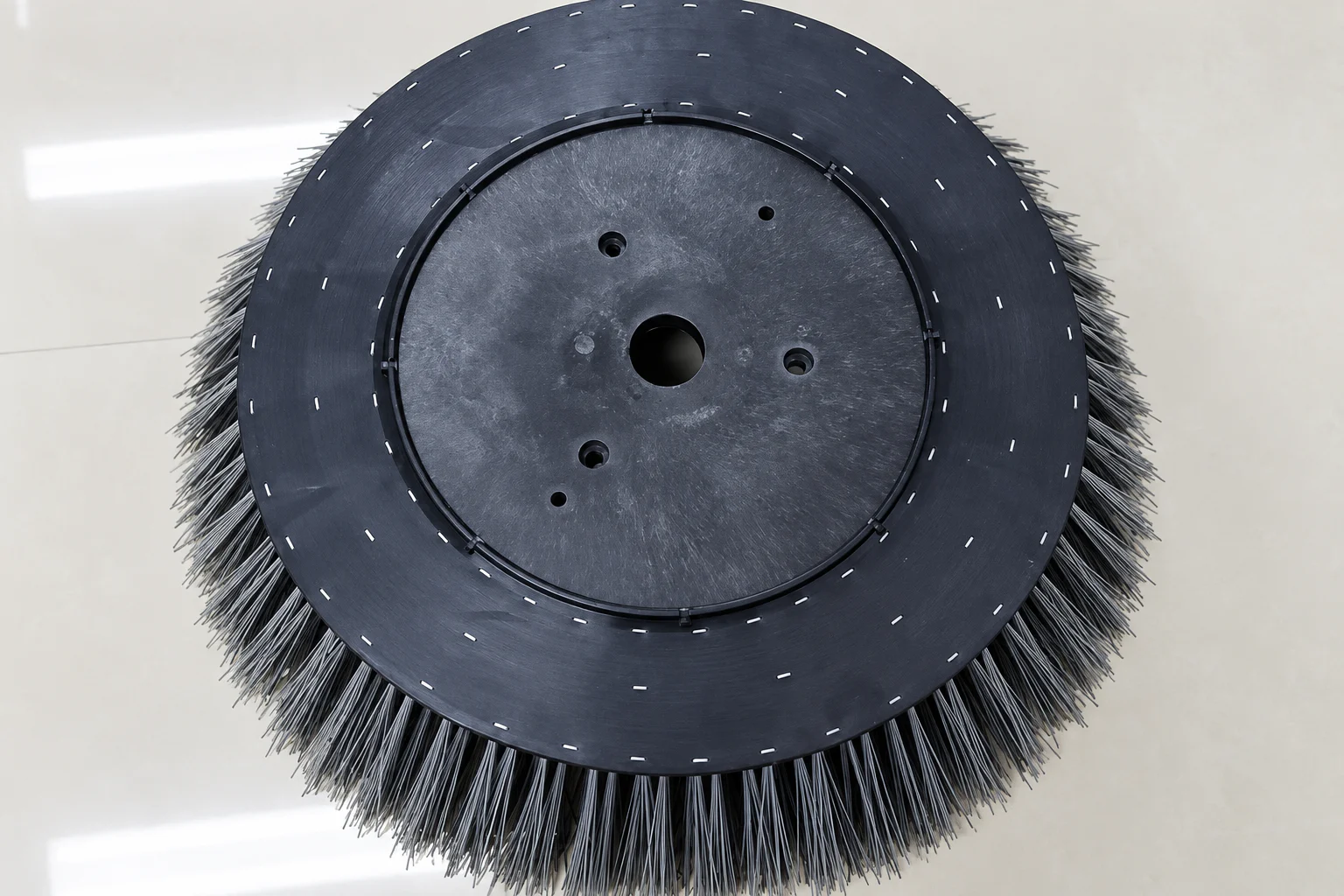 Black polypropylene gutter broom with circular mounting plate and bolt pattern