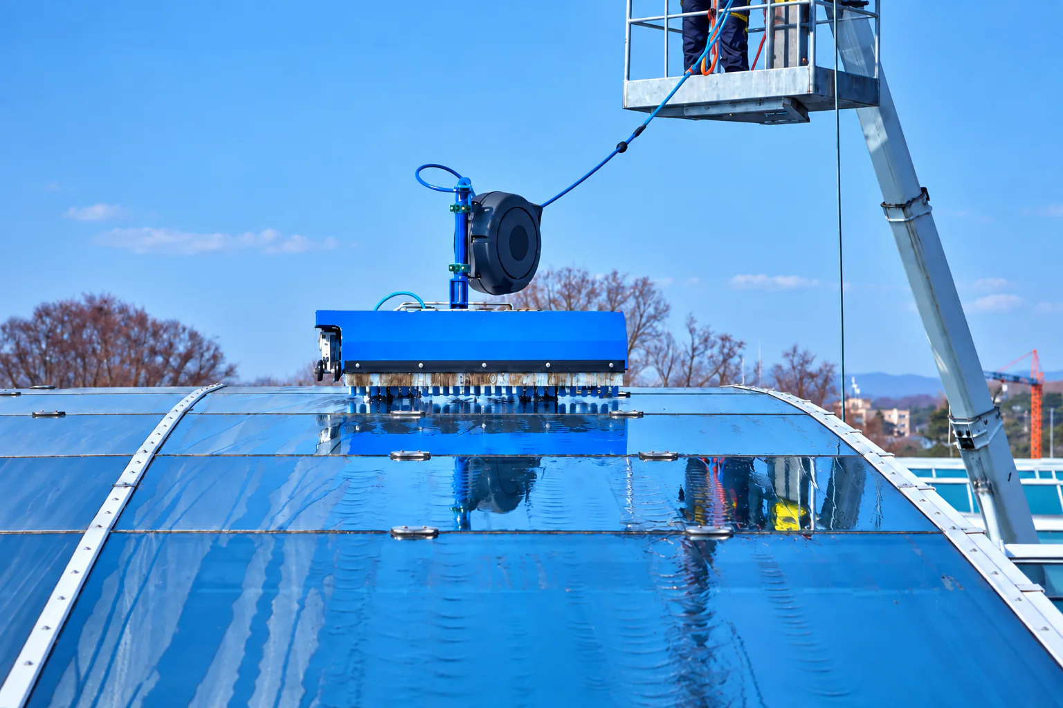 Powered brush cleaning a curved glass roof for an automated cleaning system