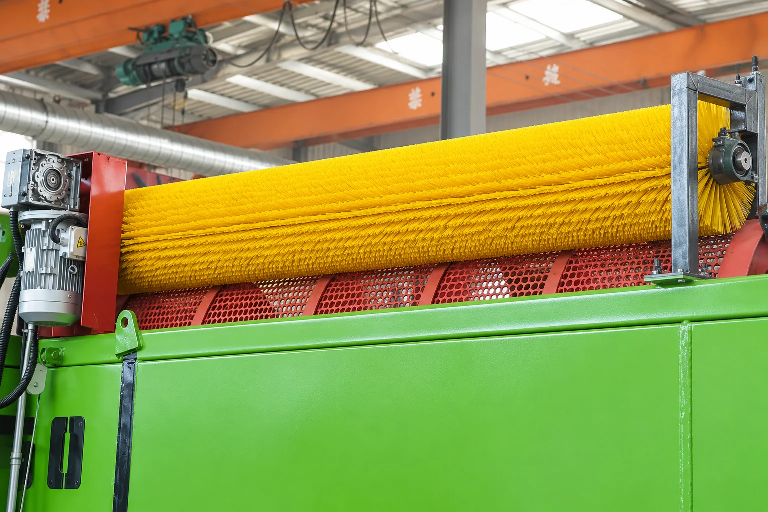 Yellow cylindrical cleaning brush installed on a stationary trommel screen