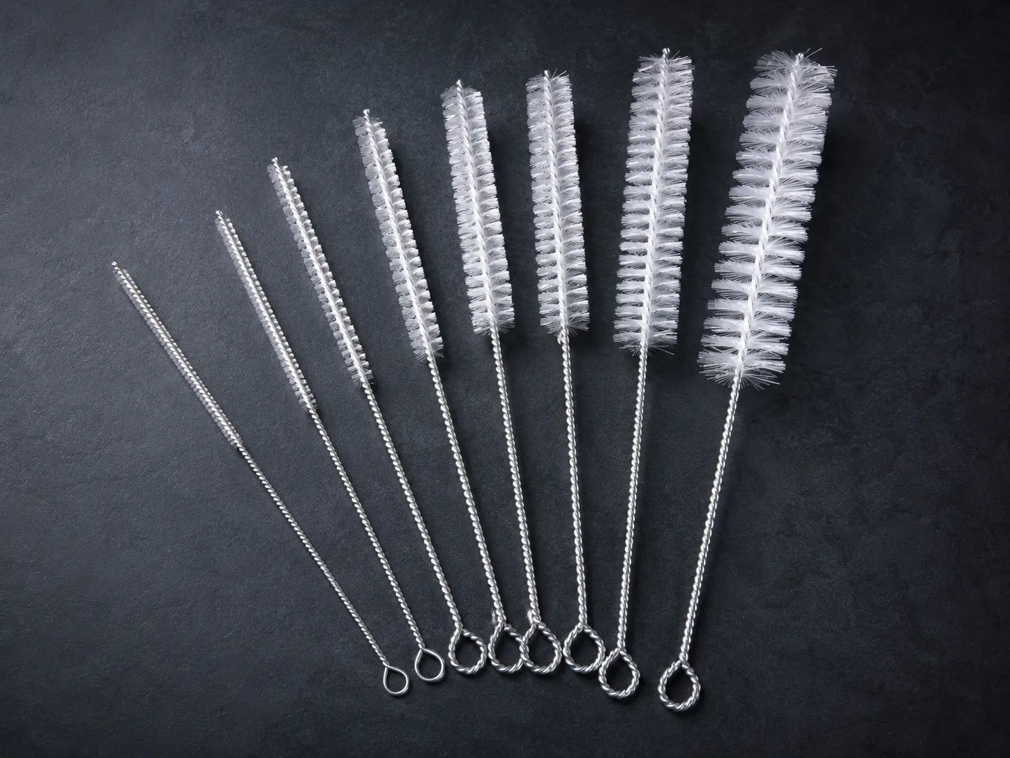 Nylon pipe and tube brushes in multiple diameters on a dark background