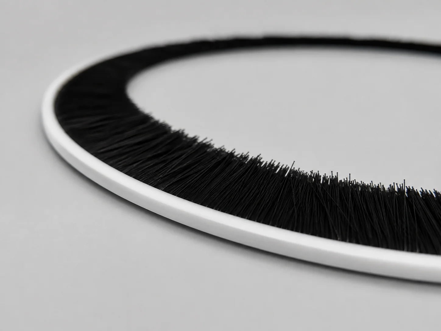 Fused extruded flexible strip brush supplied in a continuous coil