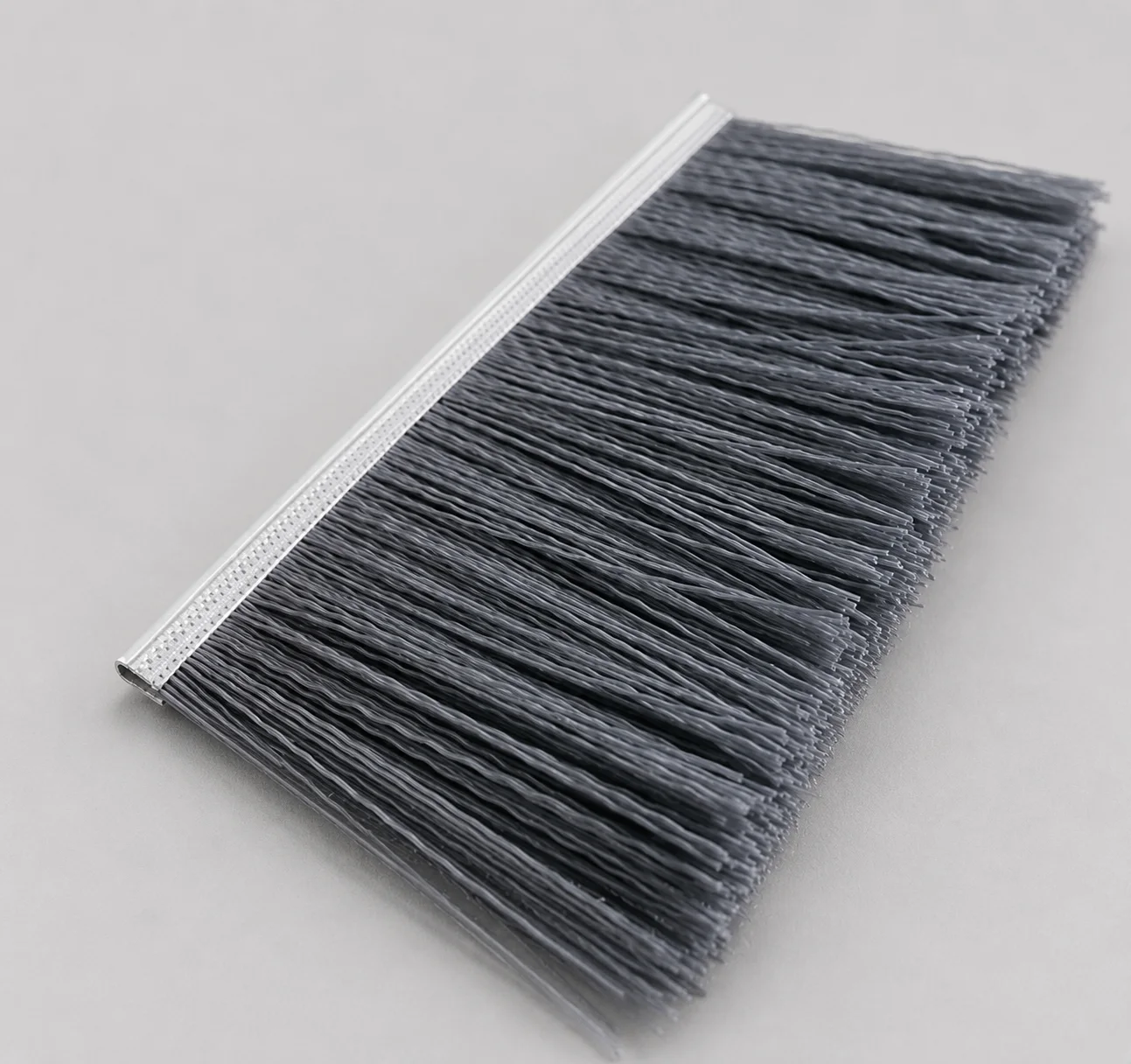 Abrasive nylon filament for application-specific strip brush contact