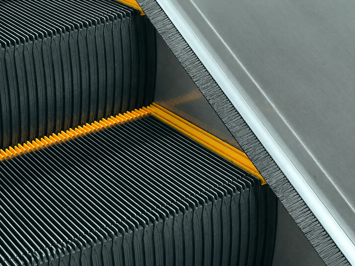 Strip brush seal installed along the moving edge of an escalator