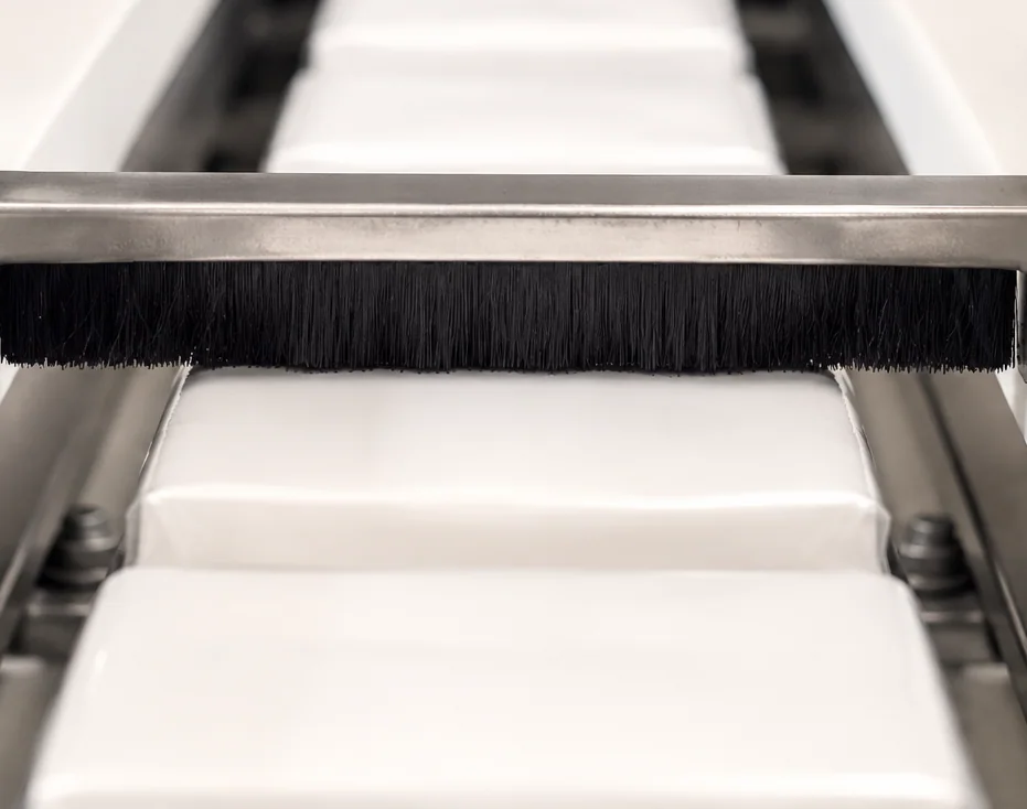 Strip brush guiding and separating products on a conveyor line