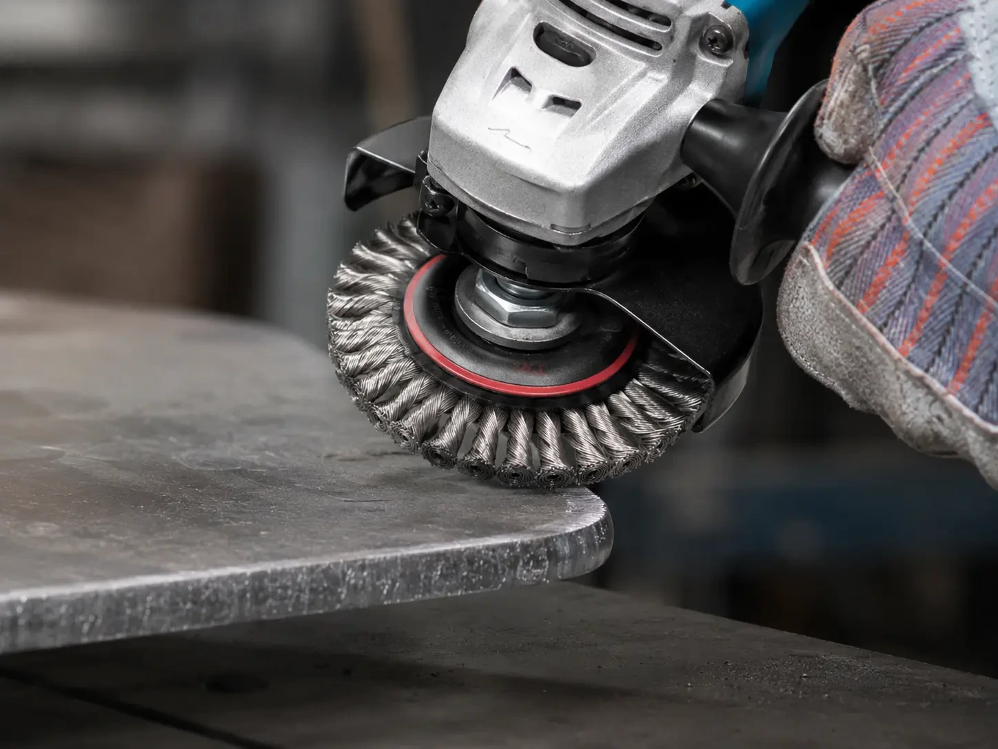 Wire wheel brush performing edge deburring on a metal workpiece