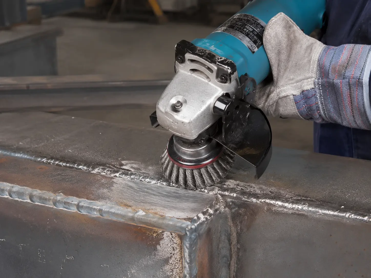 Wire wheel brush cleaning a weld seam on metal